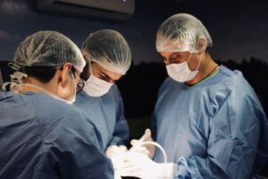 Equipe cirúrgica em centro cirúrgico durante procedimento odontológico